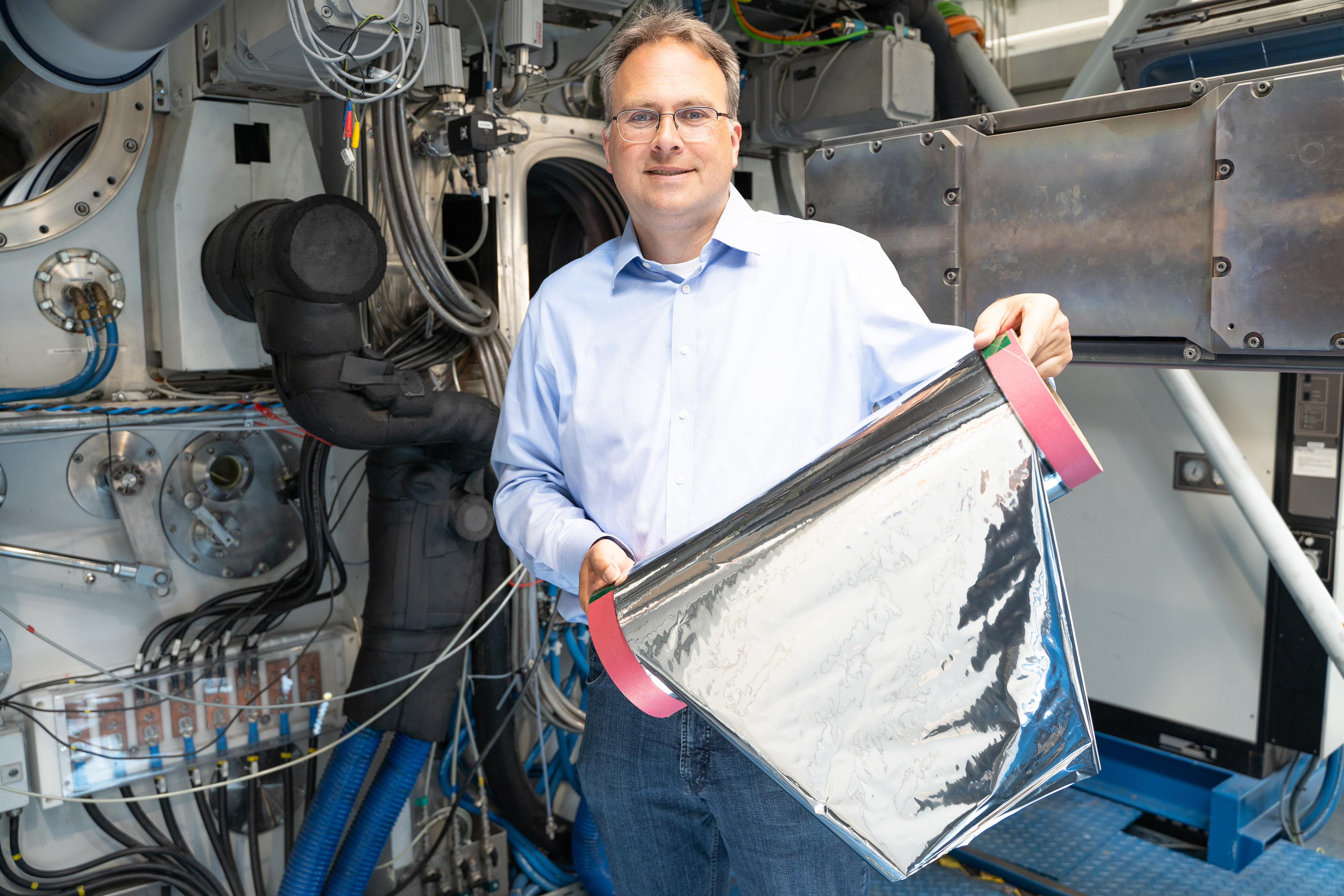Projektleiter Claus Luber zeigt das Muster einer mittels Elektronenstrahlverdampfung mit Aluminium beschichteten Kunststofffolie